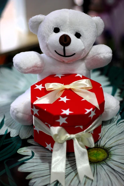 KUCAĞINDA İÇERİSİNDE GÜL YAPRAKLARI İLE SÜSLENMİŞ HEDİYE KUTUSU TAŞIYAN 25cm SEVİMLİ PELUŞ AYICIK ürün görseli